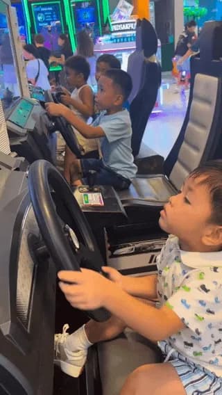 Kid taking the Initial D arcade game very seriously