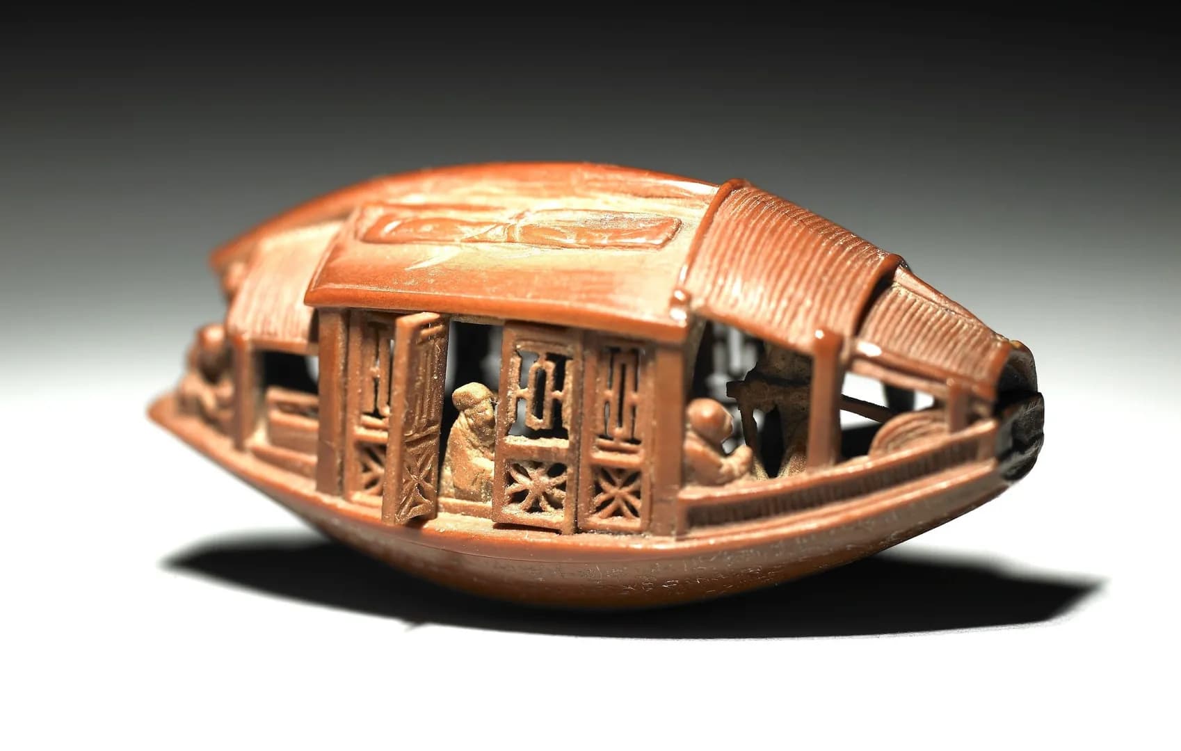 This is a miniature carved art piece on an olive pit from the Qing dynasty (1644–1911), measuring 3.4 cm in length, 1.4 cm in width, and 1.6 cm in height. It is currently housed in the National Palace