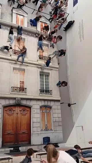 The Building" by Leandro Erlich, an art installation using a 45-degree giant mirror to make people lying on the ground look like they're dangling from a facade.