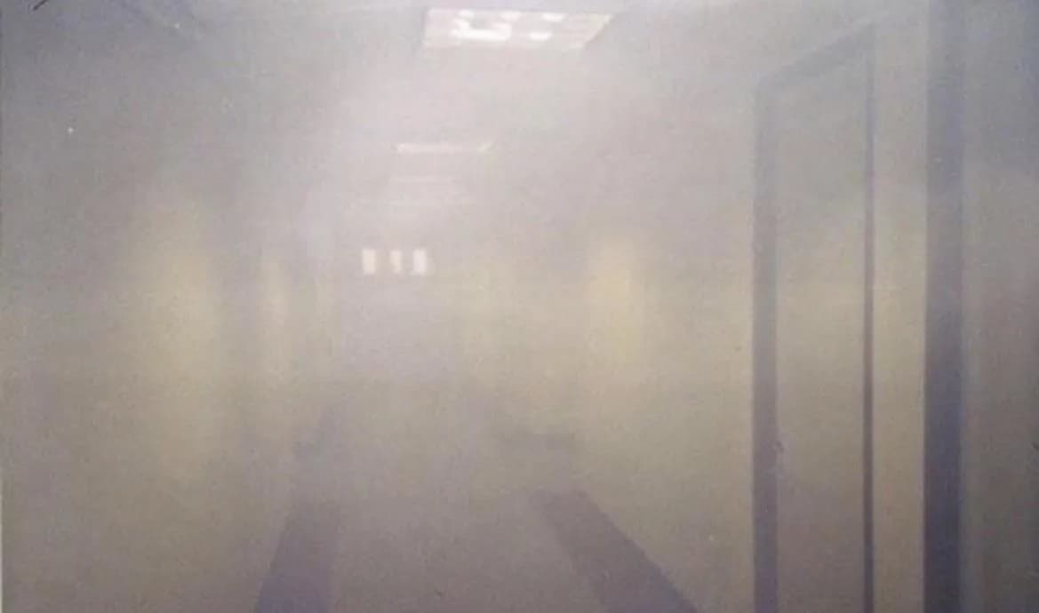 A photograph taken inside the North Tower four minutes after the plane struck, from the 77th floor. This was 18 floors below the impact zone, showing smoke and debris spreading through the building.
