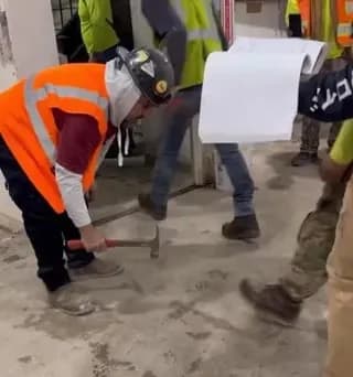 Supervisor using hammer to ensure employees are wearing safety boots.