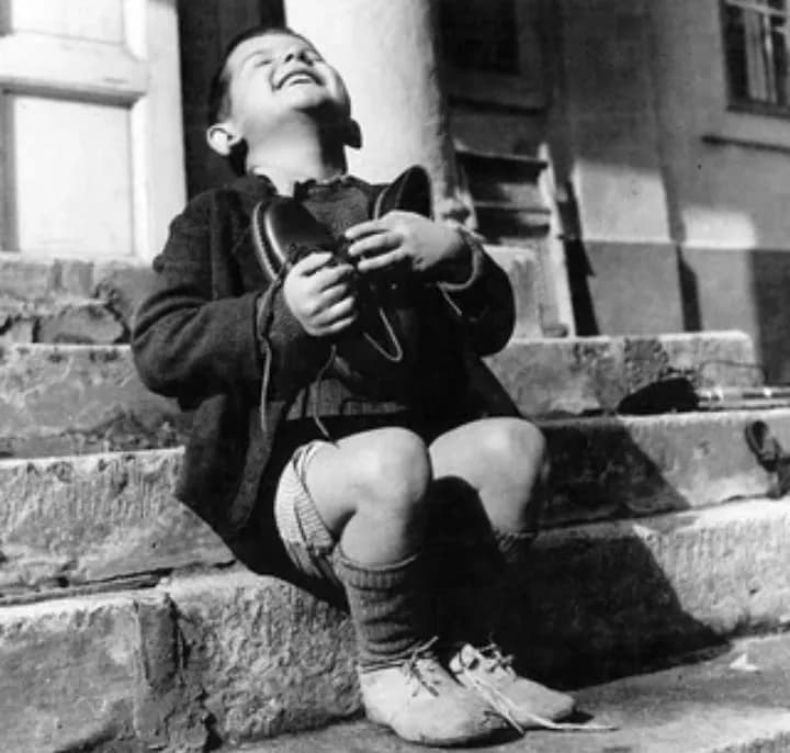 Six-year-old Austrian boy receiving a new pair of shoes at the Am Himmel orphanage, donated by the Junior Red Cross in America.