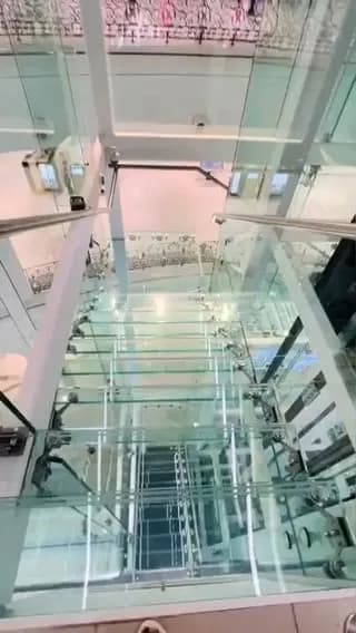 Going down a transparent glass staircase in shopping mall