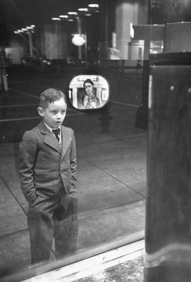 A boy watching TV for the first time in an appliance store window 1948
