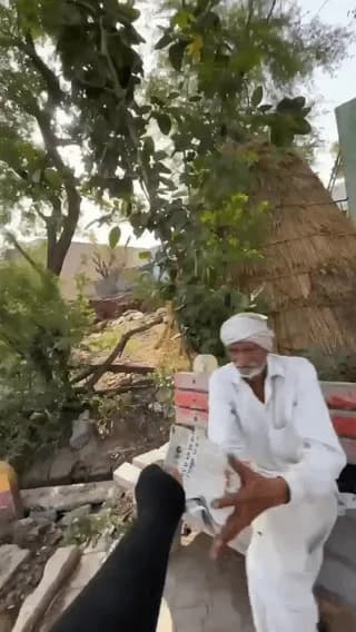 An indian Guy Delivering newspaper while riding his bike.