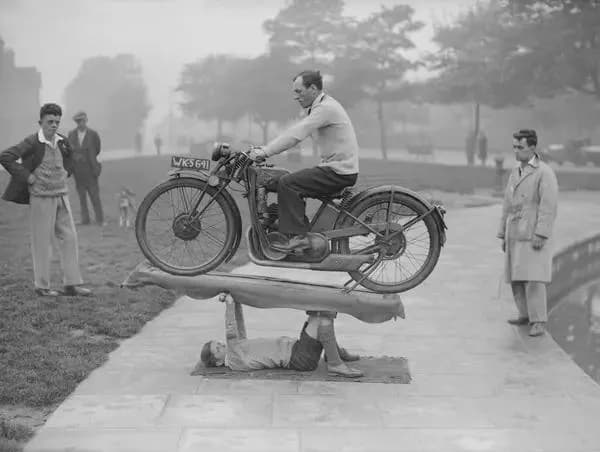This is Boy Samson the 14-year-old "strongest boy in the world" holding up a grown man on a motorcycle circa 1932